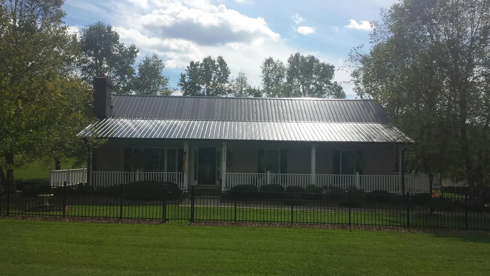 Gray metal roof on a brick ranch with a full width front porch — Gutter Guard Installation work by our crew in Onalaska
